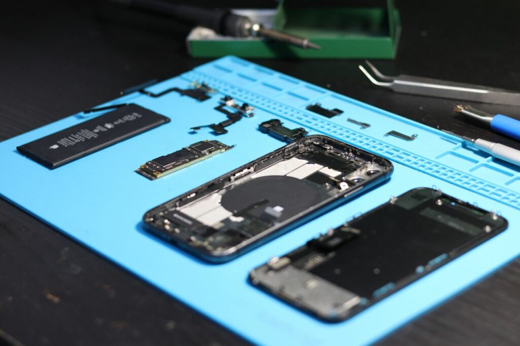 Disassembled smartphone with tools on a workbench, emphasizing repair and technology.